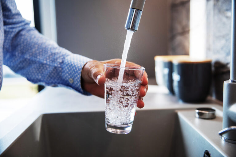 Man Filling Water Glass From Faucet