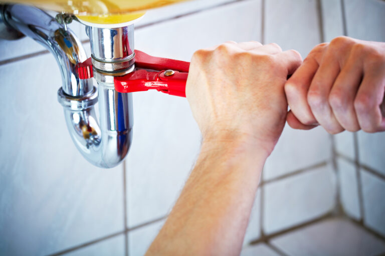 Hands Using Wrench to Fix Bathroom Sink