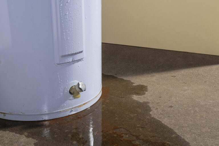 A domestic water heater leaking with signs of rust and iron in the water - Affordable Plumbing Leaking Water Heater